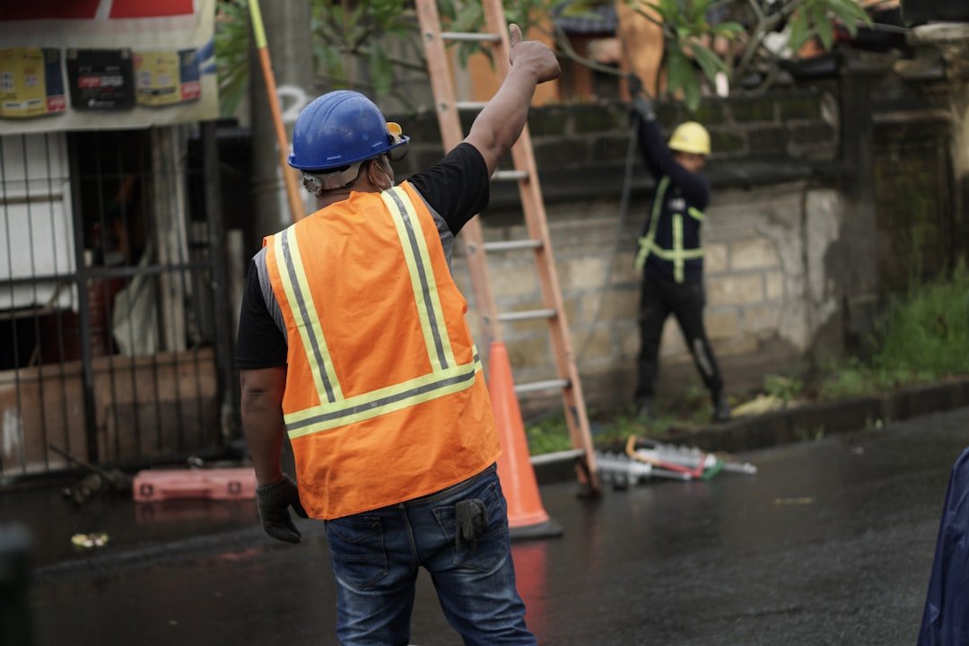 a-man-in-an-orange-safety-vest-and-a-ladder-3qmhne89a5g